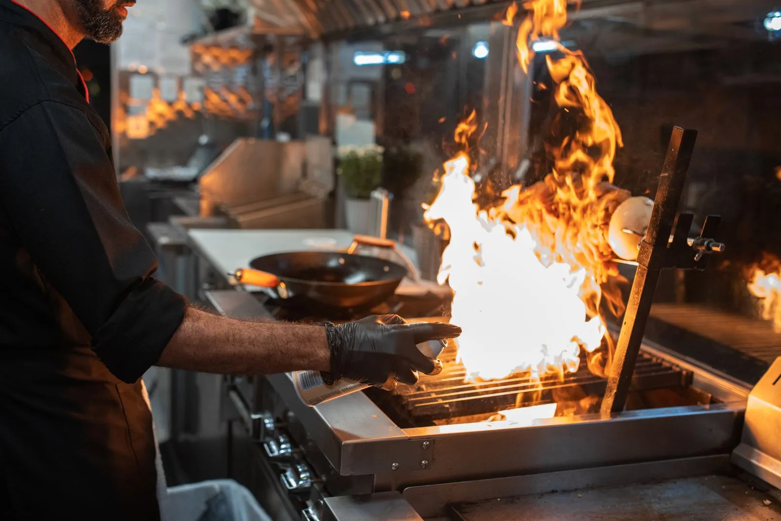 A chef sears meat over tall flames
