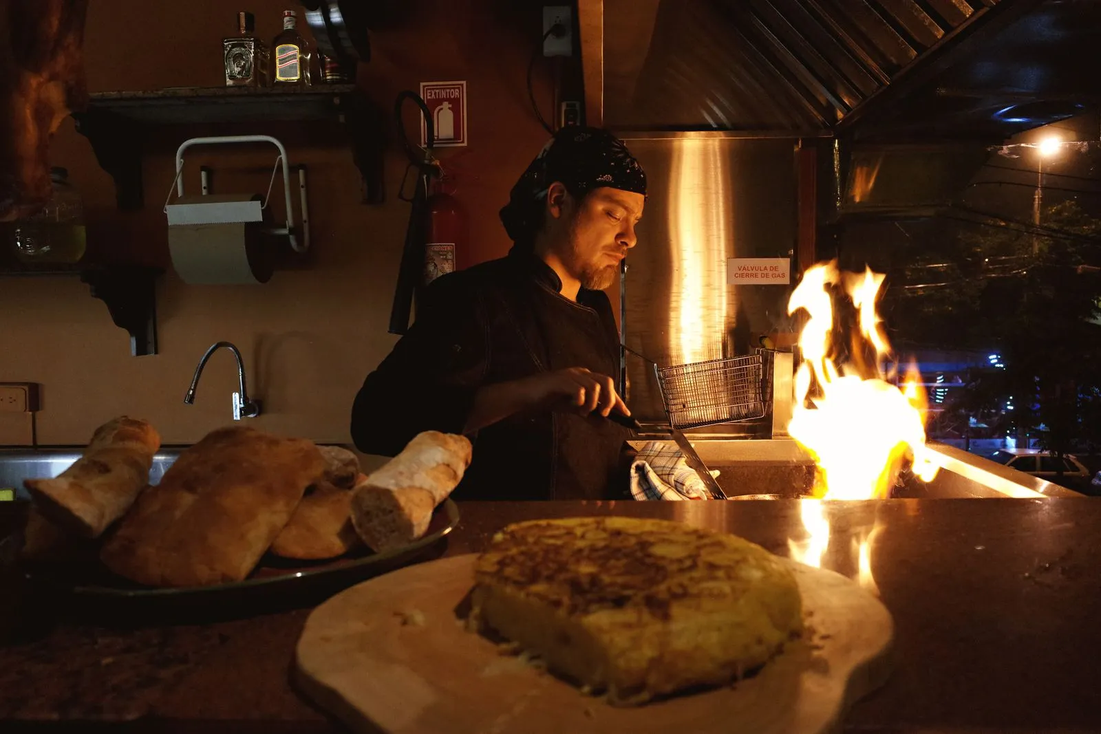 A cook prepares dishes next to a wood fire