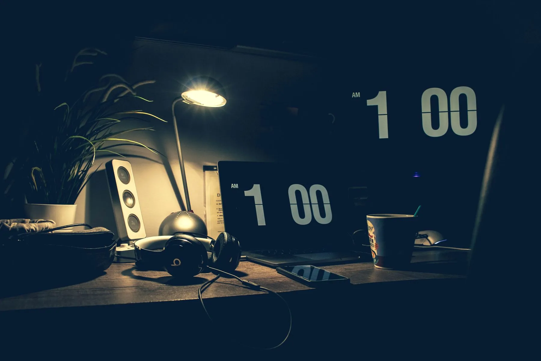 A desk in the evening, laptop and lamp on