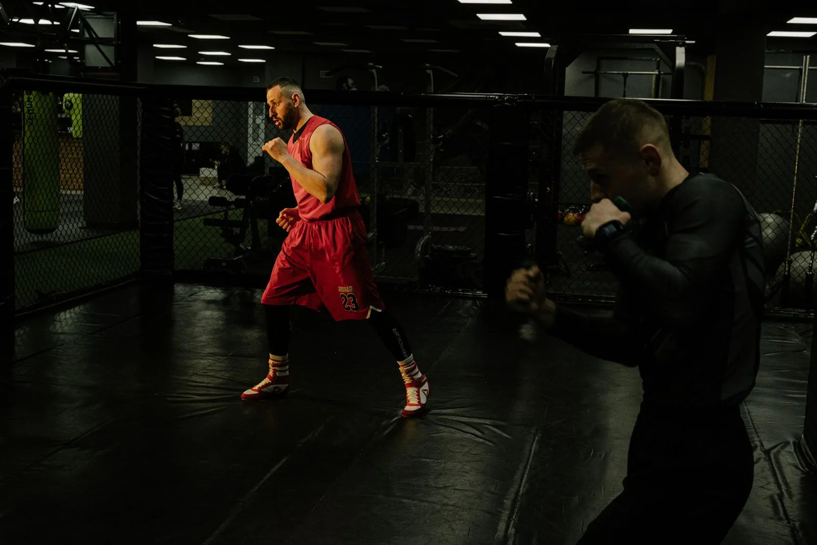 Two boxers training in a dark gym